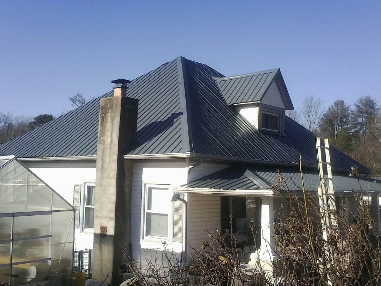 Dark blue standing seam metal roof on a white farmhouse with dormer — Slate & Tile Roof Repair by Roofing Brothers in Mendham