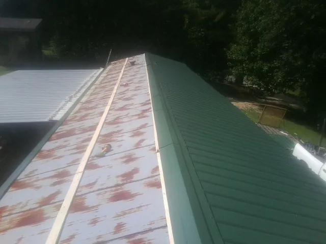 Old rusted panels beside newly installed green metal roofing — Wind Damage Roof Repair by Roofing Brothers in Mendham