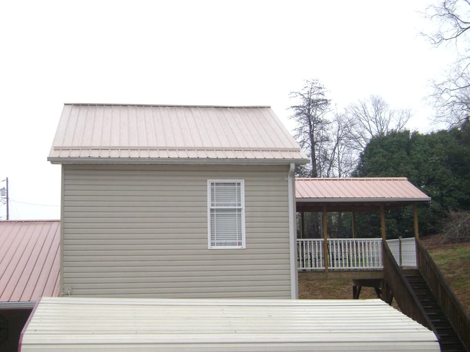 Tan metal roofs on a two story addition and attached porch, from a Roof Replacement job in Mendham