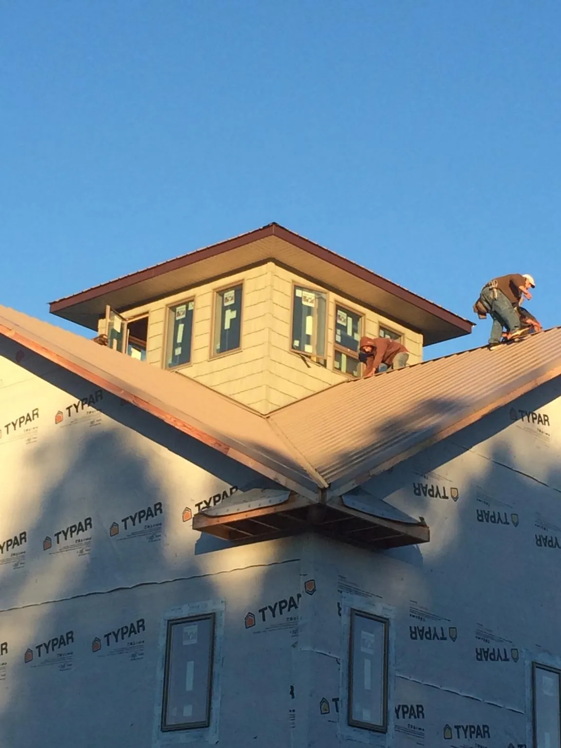 Roofers working around a rooftop cupola on a new metal roof at sunset — Roof Waterproofing in Mendham by Roofing Brothers